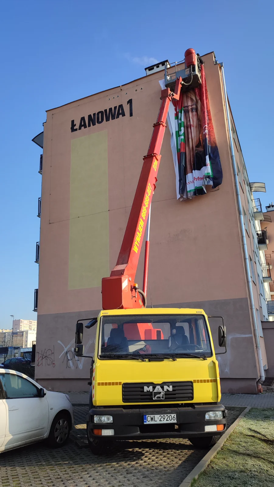 Montaż siatki reklamowej z podnośnika koszowego